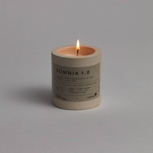 Candela aromatica Somnia 1.0 di Momo Cotton con fiamma accesa su sfondo grigio