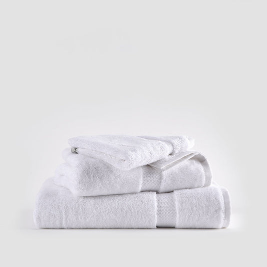 Set di asciugamani in bambù bianco impilati ordinatamente con asciugamani viso, mani e bagno con bande rigate.