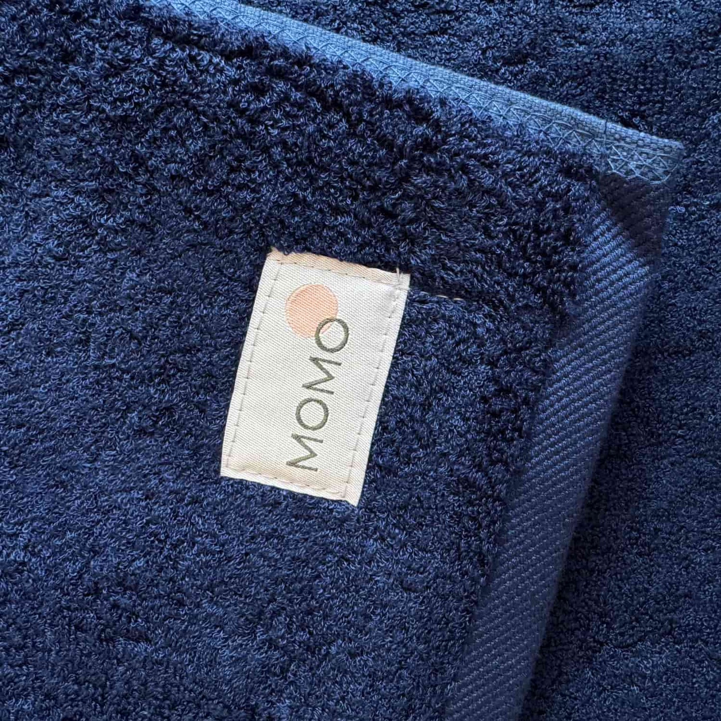 Navy blue Wabi-sabi bath mat by Momo Cotton with brand label visible on textured fabric surface