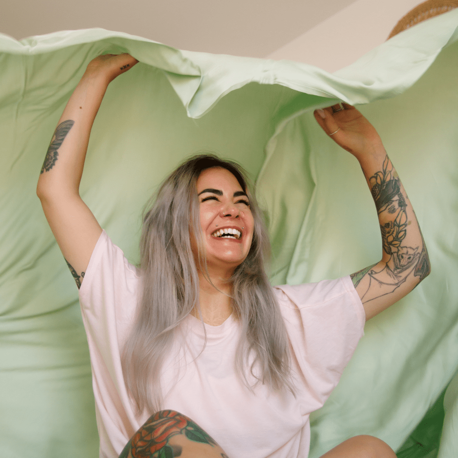 Donna sorridente che tiene biancheria da letto verde e bianca per notti estive confortevoli