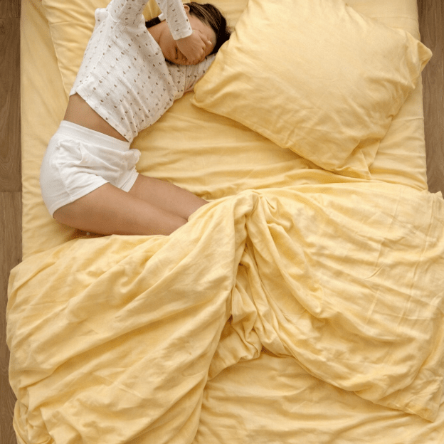 Letto con biancheria gialla e cuscino, persona sdraiata in posizione di bedscaping decorativo.