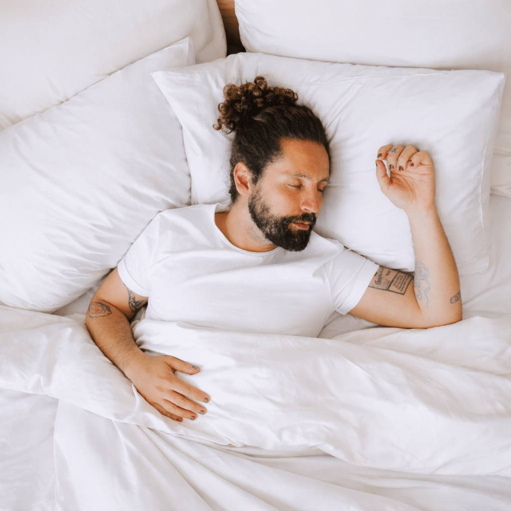 Uomo che dorme comodamente su lenzuola di bambù bianche e ipoallergeniche