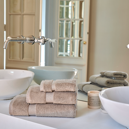 Set di asciugamani in bambù Alba impilati su un lavabo del bagno elegante con rubinetteria moderna