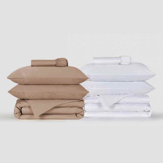 Beige and white duvet cover sets stacked together displaying folded bedding with pillows and sheets by Momo Cotton